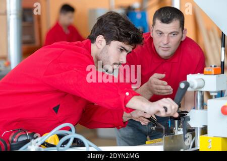 worker and apprentice standing in front of huge industrial machine