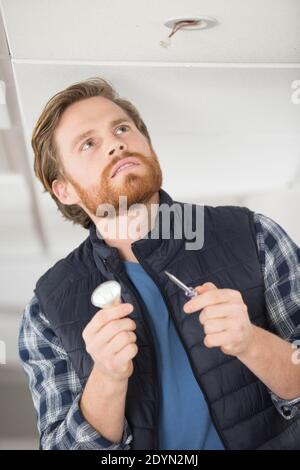 man replacing the light bulb on the ceiling Stock Photo - Alamy