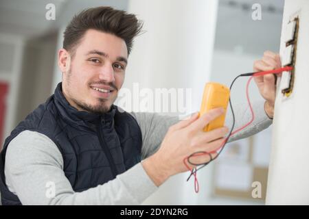 electrician checking socket voltage using multimeter Stock Photo
