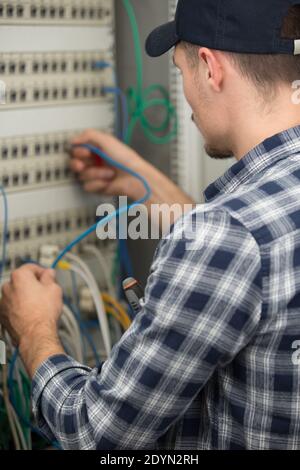 rear view of technician connecting cable in server Stock Photo