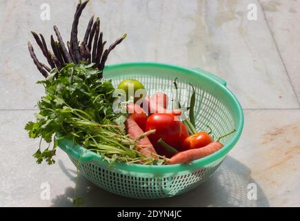 assorted colorful vegetables of winter season. carrot, tomato, coriander, beans etc.fresh harvest from home organic garden kept on plastic basket. cop Stock Photo
