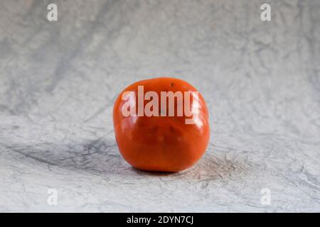 Back side of Persimmon fruit isolated with white background. Bright shiny orange color with red tint. Fresh organic fruit vegetable imported to Indian Stock Photo