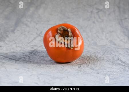 Persimmon Fruit shiney selective focus isolated on textured white background. Sharon fruit Kaki of Japan Stock Photo