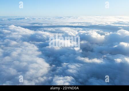 Fluffy clouds seen from above from the airplane window.  Climatology and weather concept. Stock Photo