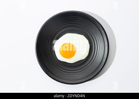 Fried egg on black plate on  white background. Stock Photo