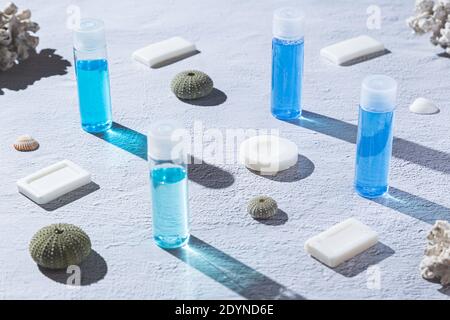 Blue and white shampoos and soaps for personal hygiene, on white background, with corals and seashells. Stock Photo