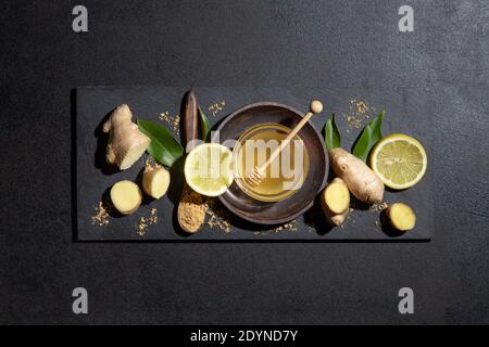 Honey, lemon and ginger on blackboard on black background. Top view.  Natural food and brevage concept. Stock Photo