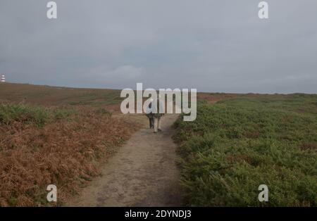 Two People Walking Along a Footpath on the Moorland of Chapel Down Heading Towards the Day Mark on the Island of St Martin's in the Isles of Scilly Stock Photo