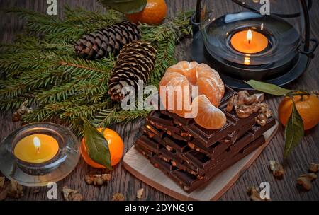 Christmas and New Year composition with tangerines, chocolate and walnuts on the dark background Stock Photo