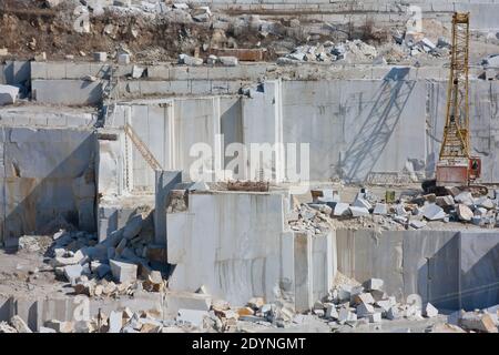 Straight walls from quarrying marble blocks in a quarry. Crawler Crane inside a career Stock Photo