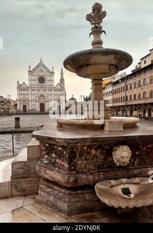 The fountain with an octagonal base, Piazza Santa Croce, Florence. The Basilica facade (in the background) on the opposite side of the square. Stock Photo