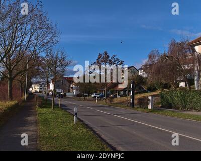 Black colored speed camera for traffic control at eastern village entrance with road and residential buildings on sunny day in winter season. Stock Photo