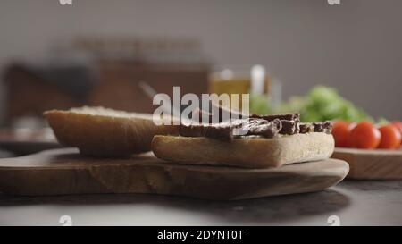 steak slices on on small ciabatta bun for sandwich on kitchen countertop, wide photo Stock Photo