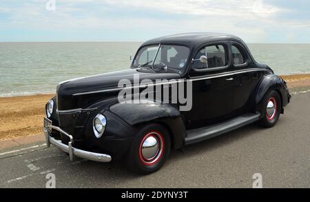 Classic Black Ford Deluxe Coupe parked on seafront promenade. Stock Photo