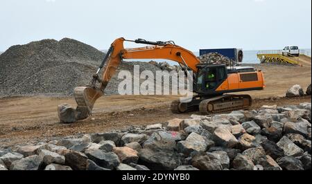 Digger moving large boulders on construction site. Stock Photo