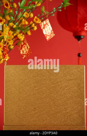 Box wrapped in golden paper, vase with apricot blooming flowers and paper lantern for Tet celebration Stock Photo
