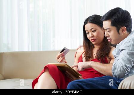 Young multi-ethnic couple with credit card spending time together and making online purchases Stock Photo