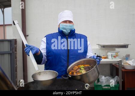 Cooking street food during the coronavirus panademy. A chef in a medical mask with a large scoop. Stock Photo