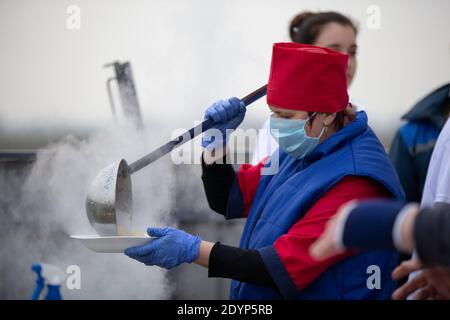 November 13, 2020. Belarus, Gomil region. PA Cooking street food during the coronavirus panademy. A chef in a medical mask with a large scoop pours so Stock Photo