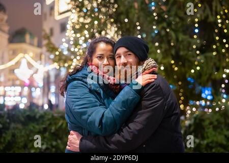 Happy young mulinational couple outdoor in a city center at Christmas Stock Photo