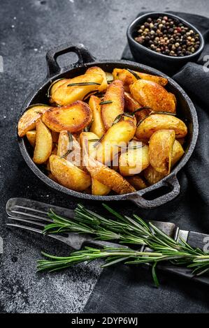 Fried potato wedges, French fries in a pan. Black background. Top view Stock Photo