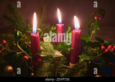 Natural Christmas table centrepiece with three red candles, ivy, holly and pine Stock Photo