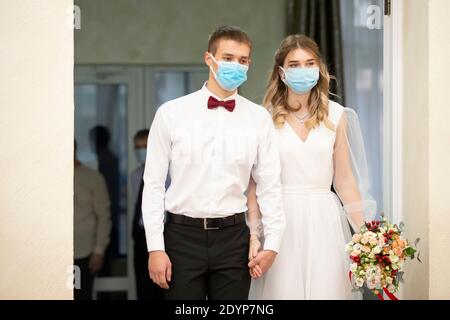 Bride and groom wearing medical masks. Getting married during the coronavirus pandemic. Stock Photo