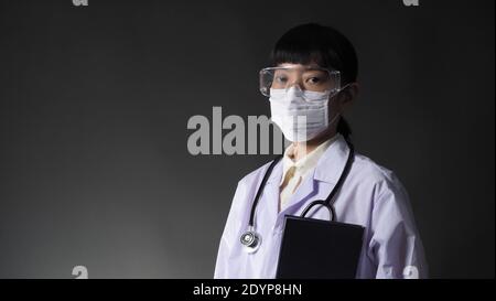 Doctor Wearing Medical Mask and clear goggles or glasses and stethoscope on the neck and white uniform. Asian female doctor or scientist in protective Stock Photo
