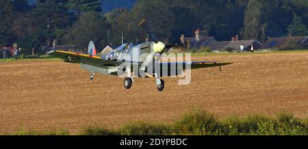 :Vintage Supermarine Spitfire MK Vc G-AW11 AR501 aircraft Landing with wheels down. Stock Photo