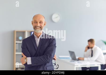 Smiling man office worker standing and looking at camera over colleague working at background Stock Photo