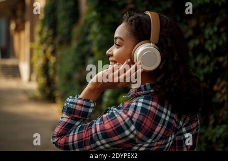 Cheerful woman in headphones rests in summer park Stock Photo