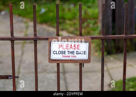 A please close the gate sign hanging on a rusty metal gate Stock Photo