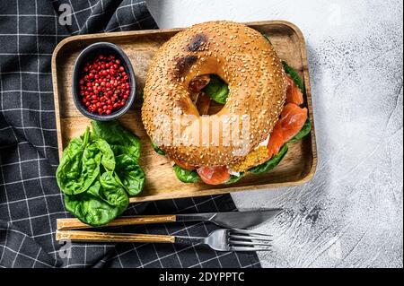 Healthy freshly baked bagel filled with smoked salmon, spinach and egg. Gray background. Top view Stock Photo