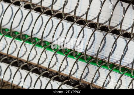 A macro shot of stack of spiral notebooks is turned into an abstract of metal and shadows. Stock Photo