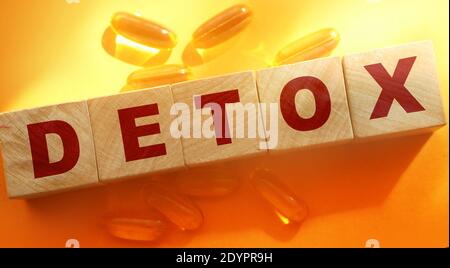 Detox word made with wooden blocks and oil capsuless around on orange background. Medical healthcare concept Stock Photo