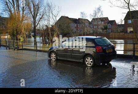 Toyota car parked in flooded area of town with railings and trees Stock Photo