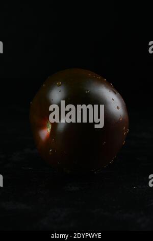 Black tomato - Kumato on the black background. Stock Photo