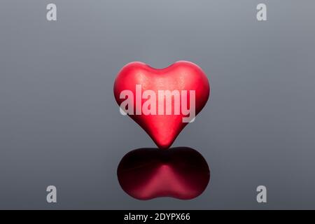 volumetric symbol of a heart of red on a black background with reflection, a symbol of health and love on the medical theme of celebrating Valentine's Stock Photo
