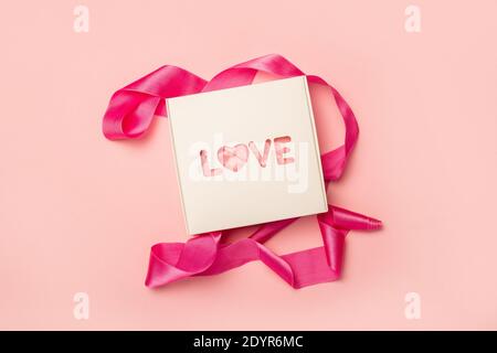 Gift box and pink ribbon on a pastel pink background. Composition Valentine's Day. Flat lay, top view. Banner. Stock Photo