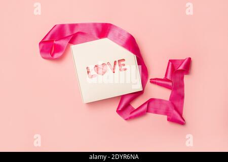 Gift box and pink ribbon on a pastel pink background. Composition Valentine's Day. Flat lay, top view. Banner. Stock Photo