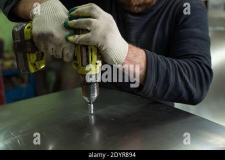 Man Works in Auto Workshop with Cordless Screwdriver Stock Photo