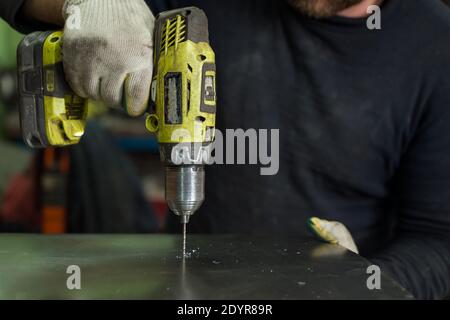 Man Works in Auto Workshop with Cordless Screwdriver Stock Photo