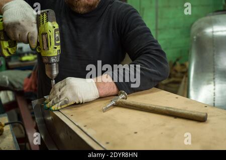Man Works in Auto Workshop with Cordless Screwdriver Stock Photo