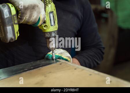 Man Works in Auto Workshop with Cordless Screwdriver Stock Photo