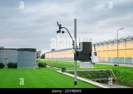 Weather station for measuring temperature, humidity and wind speed in a greenhouse area. Cups of anemometer are a bit blurred due to the wind. Stock Photo