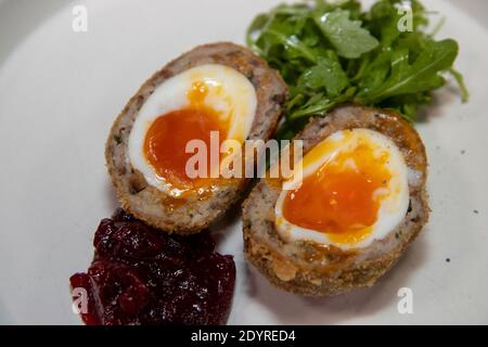 A delicious home made scotch egg on a white plate with salad Stock Photo