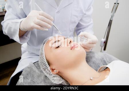 Dermatologist's putting nutrition mask on the young and beautiful woman skin after cleaning to make her skin smooth and healthy. Stock Photo