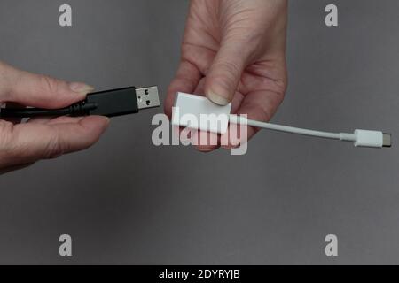 hands connecting a usb cable to a usb-c to usb adaptor on a gray background Stock Photo