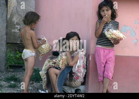 Gypsy (Rroma/ Romani) children  in Romania snacking on cheap puffed corn Stock Photo