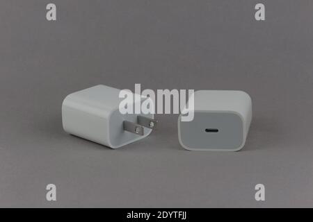 white USB-C 20 watt power adapter, front and back ends showing, on a grey background Stock Photo